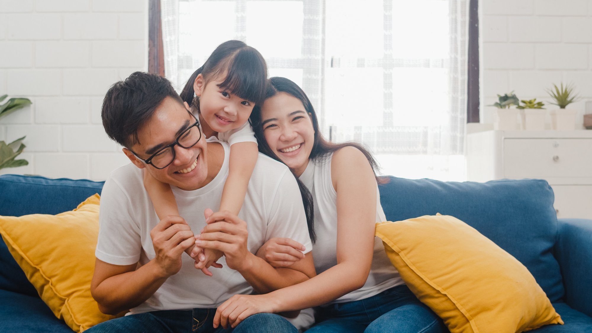 A family sharing a warm moment on a blue sofa with yellow cushions