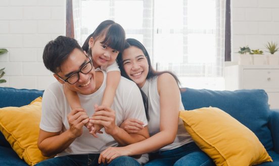 A family sharing a warm moment on a blue sofa with yellow cushions